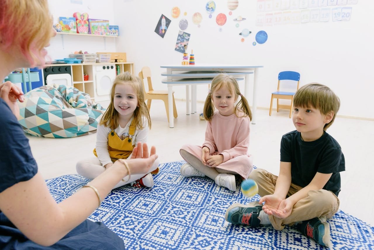 Happy children sitting indoors, enjoying fun learning activities in a kindergarten setting.